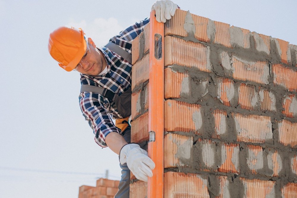 Ouvrier en train de construire un mur en briques sur un chantier.