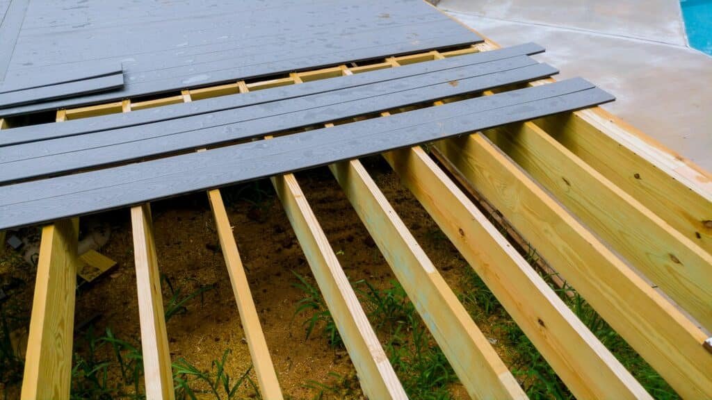 Construction d'une terrasse en bois avec des planches alignées et des poutres en cours d'installation.