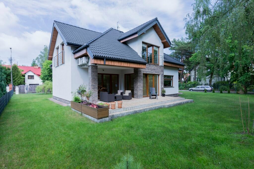 Maison moderne avec toiture en ardoise, disposant d'une grande terrasse et d'un jardin soigné, située dans un quartier résidentiel.