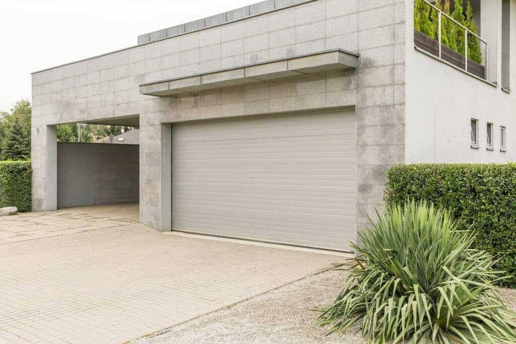 Porte de garage intégrée dans un mur de briques blanches, donnant un aspect épuré et moderne à l'entrée de la maison.