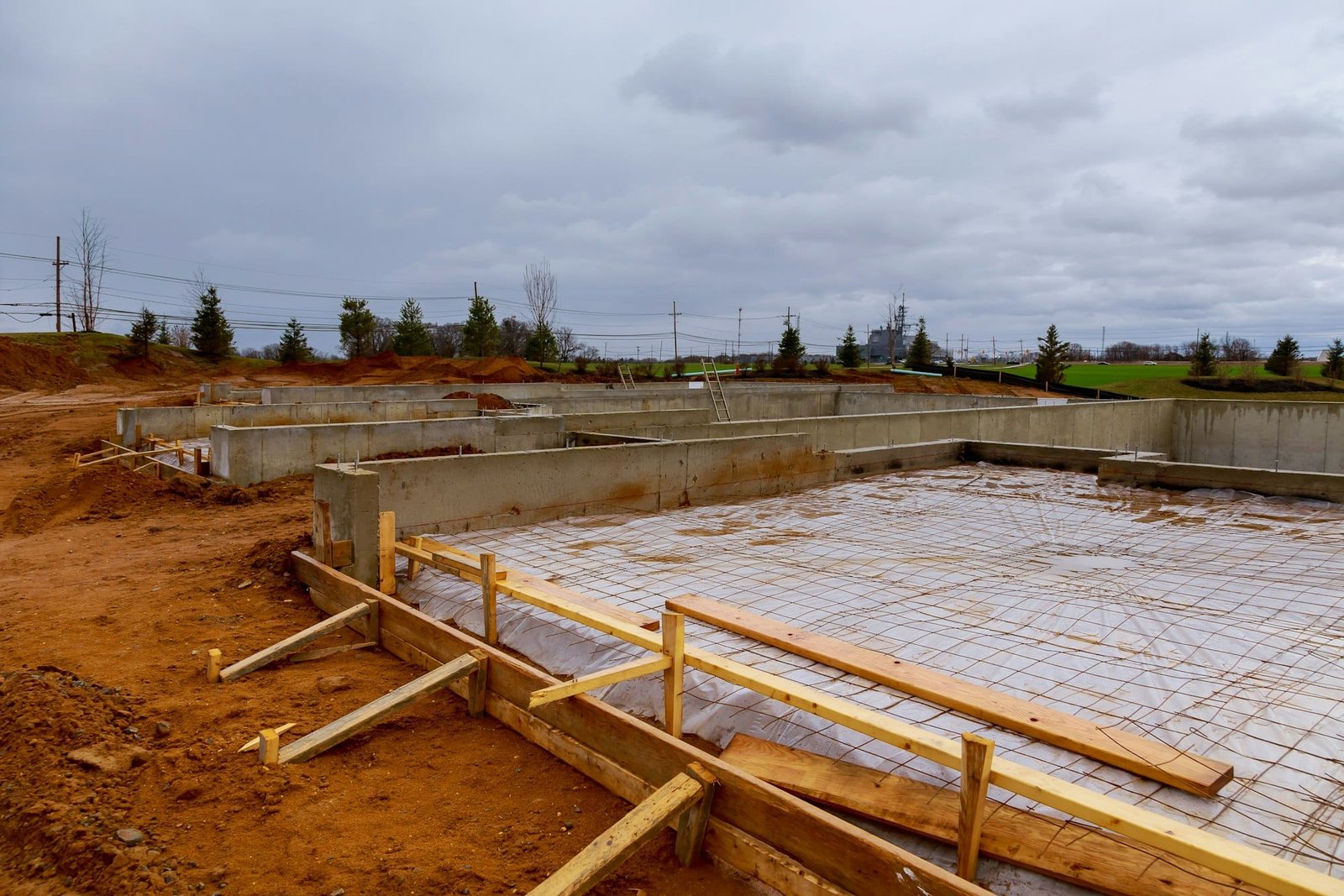 Site de construction avec préparation des fondations pour le coulage du béton, renforcé par des barres d'armature et un cadre en bois.