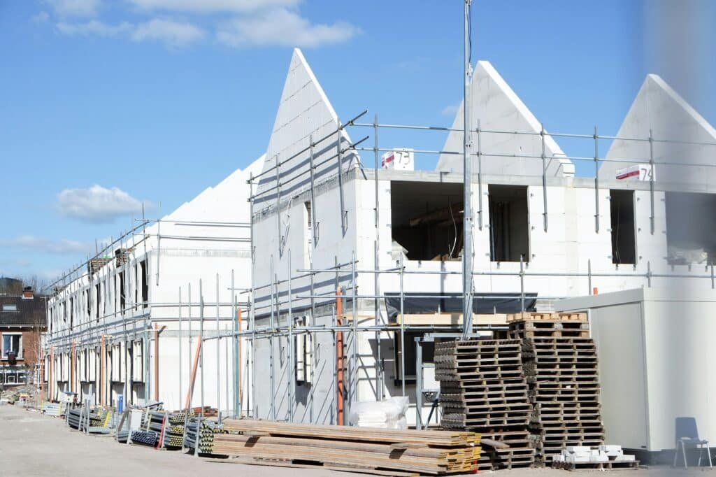 Vue sur la construction d'une maison avec des échafaudages et des matériaux de construction éparpillés autour des structures.